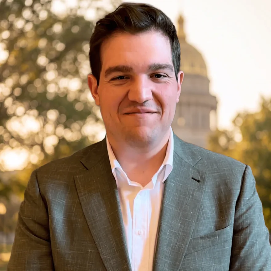 Jason Cruz in a sage green suit in front of the Colorado State Capitol dome at golden hour